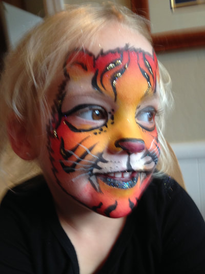 A smiling boy with an orange tiger face